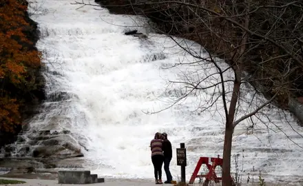 A couple kisses as water gushes down a waterfall at Buttermilk Falls State Park, Monday, Oct. 30, 2017, in Ithaca, N.Y. (AP Photo/Julio Cortez)