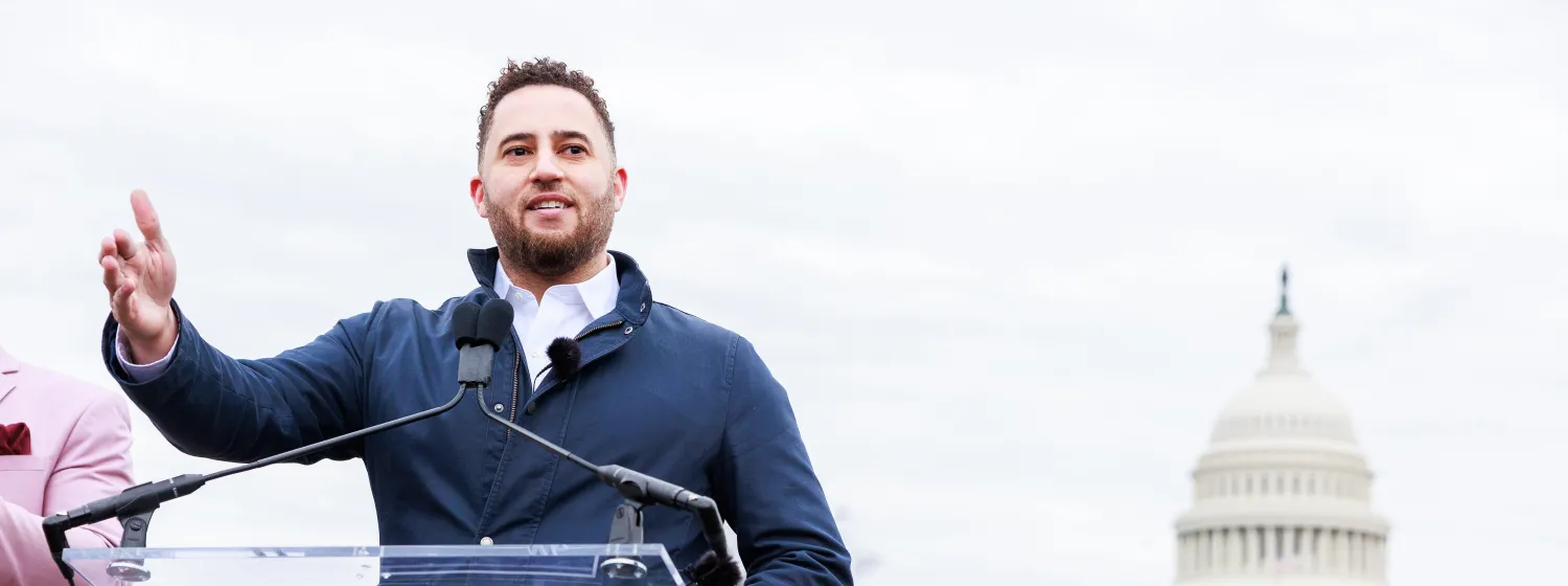 Svante Myrick standing at a podium in front of the Capitol building.