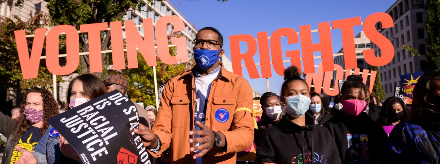 Image of protesters with large letters that say "voting rights" behind them