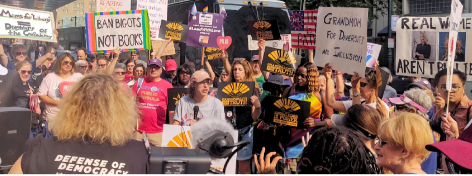Protesters hold signs at an event objecting to book bans