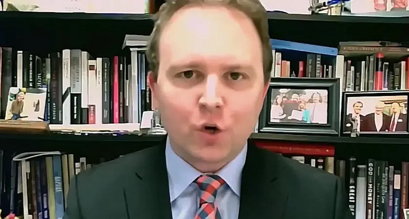 David Closson, a white man with a receding hairline wearing a suit and tie, is seated in front of bookshelves.