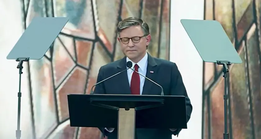 House Speaker Mike Johnson pictured standing at a lectern on the outdoor stage at the Rededicate 250 event.