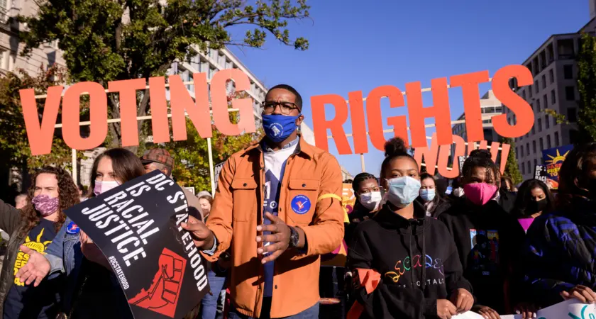 Image of protesters with large letters that say "voting rights" behind them