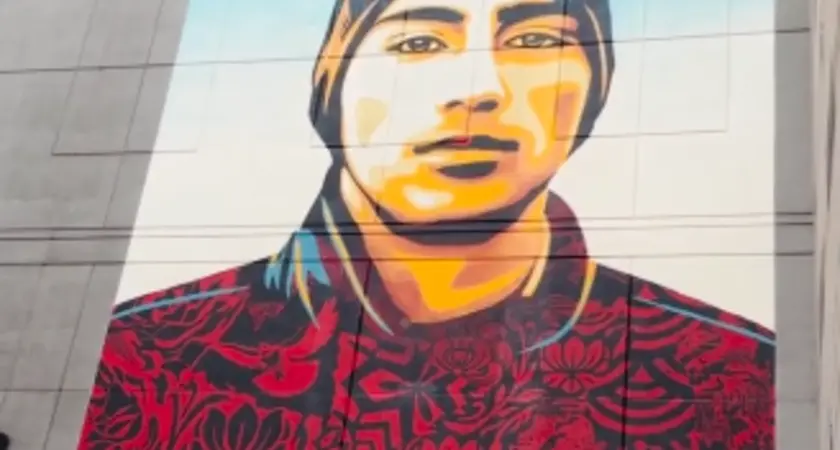 A mural of a young man with text that says "demand change"