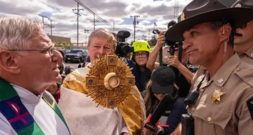 A member of Illinois State Police relays the message to priests that ICE denied them access to detainees to provide them communion, outside a U.S. Immigration and Customs Enforcement facility in Broadview, Ill., Saturday, Oct. 11, 2025. (AP Photo/Adam Gray)