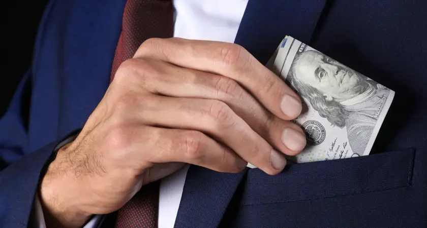 A man puts a $100 bill into his jacket pocket