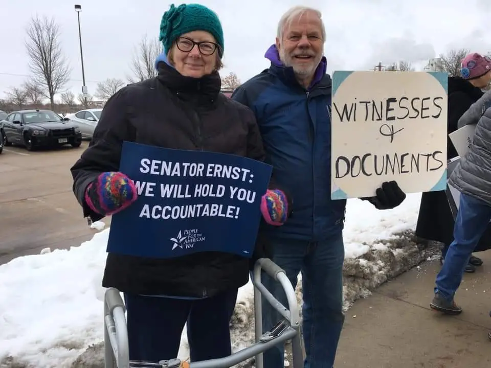 Two PFAW supporters hold signs outside of Sen. Joni Ernst's office in Cedar Rapids