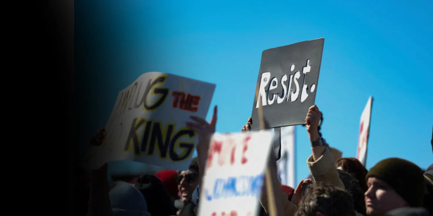 protestors holding a sign that says "resist"