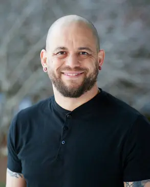 A photo of Michael Dixon, a bald man with a short beard wearing a black shirt.