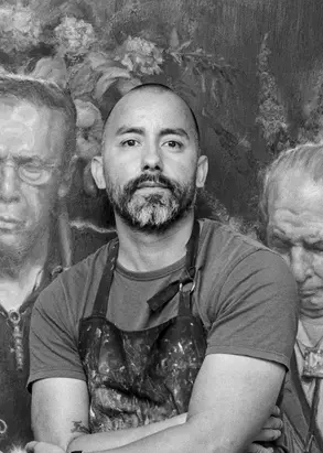 A black and white photo of Vincent Valdez, a man with buzzed hair and a beard wearing a t-shirt and apron.