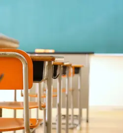 An empty classroom with desks and a chalkboard.