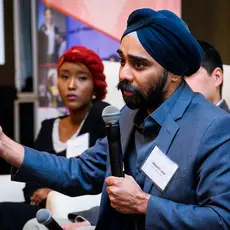 A man in a turban and suit speaking into a microphone