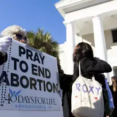 Protestors hold a sign that reads "Pray to end abortion"