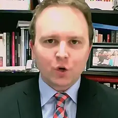 David Closson, a white man with a receding hairline wearing a suit and tie, is seated in front of bookshelves.