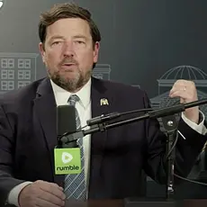 Image from Ed Martin's podcast, the Pro-America Report. Martin is seated behind a microphone emblazoned with the Rumble logo. 