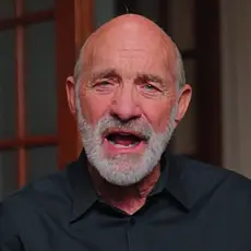 Lou Engle, a bald white man with a gray beard, is seated in what appears to be a home library, speaking directly into the camera.