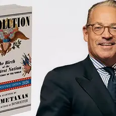 The left side of the image is a photograph of Eric Metaxas' book "Revolution." The ride side is a chest-and-head portrait of Metaxas in suit and tie smiling for the camera. 