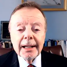 Gary Bauer, in suit and tie, is seated in what appears to be a home office. Visible behind him are some books and photos and a small model of what appears to be Michelangenlo's Pietà