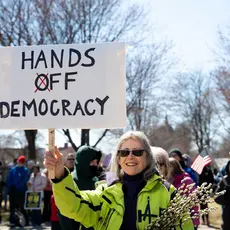 protestors holding a sign that says "hands off democracy"