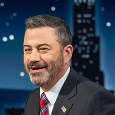 Jimmy Kimmel wearing a dark gray suit and red tie