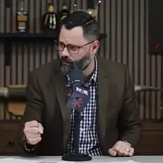 Joel Webbon, seated in his studio, clenches his right fist