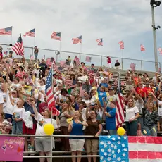 Rallygoers wave the American flag from bleachers
