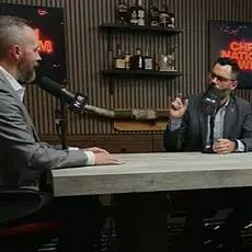 Dale Partridge and Joel Webbon are seated at a table, both with microphones in front of them; screens in the background display the text "Christian Nationalism Weekly"