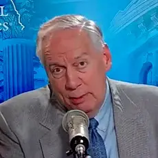 Ralph Drollinger, white man with gray hair in suite and tie, is seated and speaking into a microphone. The background includes the logo of Capitol Ministries and an illustrated collage of images including part of the Capitol dome and U.S. flag.