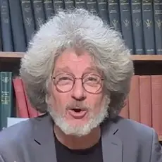 Randall Terry, white man with gray beard and full head of feathered gray hair, is seated at a microphone in front of bookshelves.