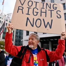 Older man holding a sign that says "voting rights now" 