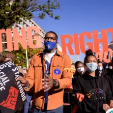 Image of protesters with large letters that say "voting rights" behind them