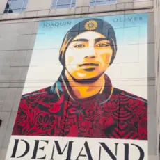 A mural of a young man with text that says "demand change"