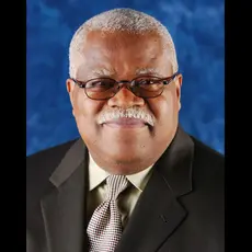 A photo of Reginald Weaver in a dark suit with a blue background