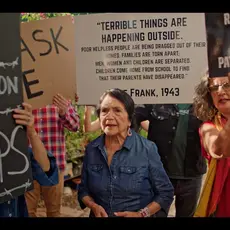 Activist Dolores Huerta surrounded by protestors rallying against ICE