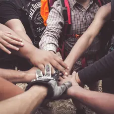 Ten people putting their hands together in the center of the group