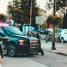 Two police arrest someone while a bystander films with a phone