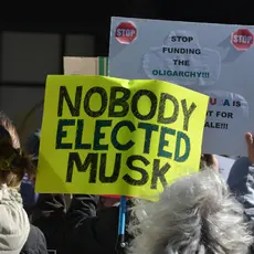 Protestors holding a sign that reads "nobody elected musk"