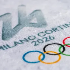 A close up of an ice rink that says "Milan Cortina 2026" and has the olympic logo