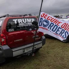 Truck with a Trump window decal and a flag that reads "secure our borders"