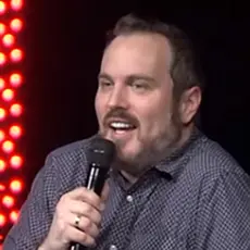 Sean Bolz, a white man with reddish brown beard, dressed casually and holding a microphone
