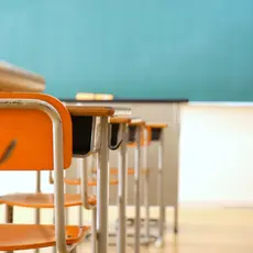 An empty classroom with desks and a chalkboard.