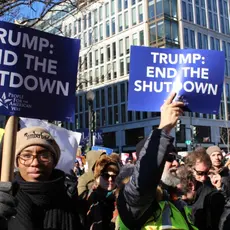 A group of people holding signs that say "Trump: End the shutdown"