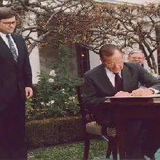 President George H. W. Bush signs the Civil Rights Commission Reauthorization Act in the Rose Garden of the White House. Beside him are Attorney General William Barr and Vice President Dan Quayle. 21 Nov 91