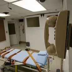 An execution chamber with a telephone and a hospital bed with straps.