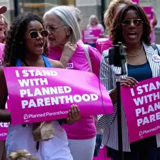 Protesters in Chicago hold pink signs that say "I stand with Planned Parenthood."