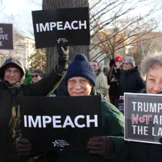Activists hold signs calling for Donald Trump's impeachment and removal.