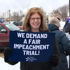 PFAW activist holds a sign outside of Senator Joni Ernst's office in Cedar Rapids
