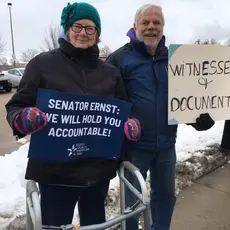 Two PFAW supporters hold signs outside of Sen. Joni Ernst's office in Cedar Rapids
