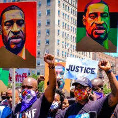 Protesters holding signs featuring George Floyd's image.