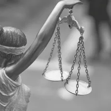 Black and white photograph of a statue of ablindfolded woman holding the scales of justice